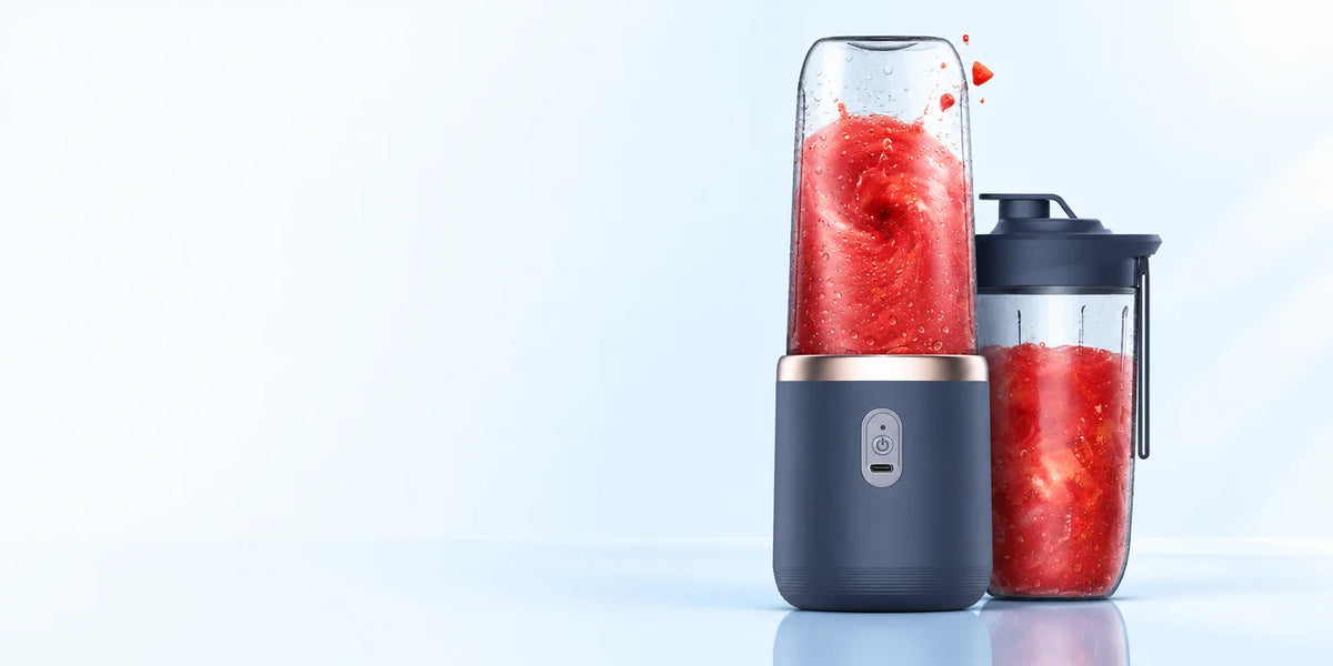 A wide hero photograph of the exact compact dark-blue portable blender with its clear blending cup a