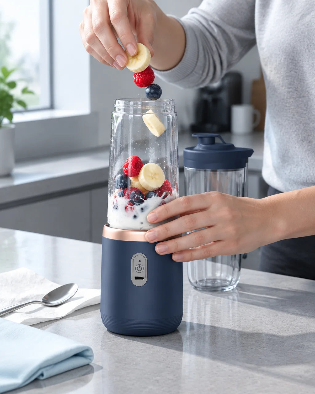 A close photograph of the exact dark-blue portable blender with its clear cup on a slightly cluttere