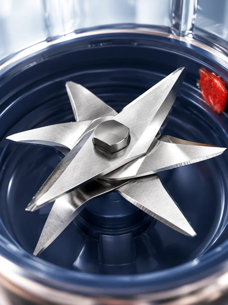 An extreme close macro photograph of the six steel blades at the base of the exact blender cup, usin