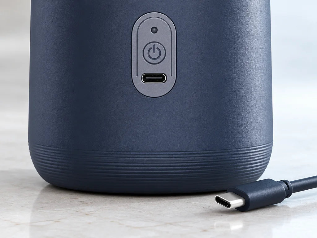 A close macro photograph of the USB-C port on the lower front of the exact dark-blue blender, preser